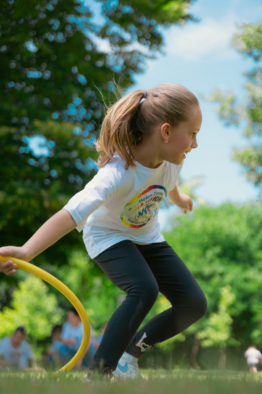 little girl running with a hula hoop during an outdoor physical education class